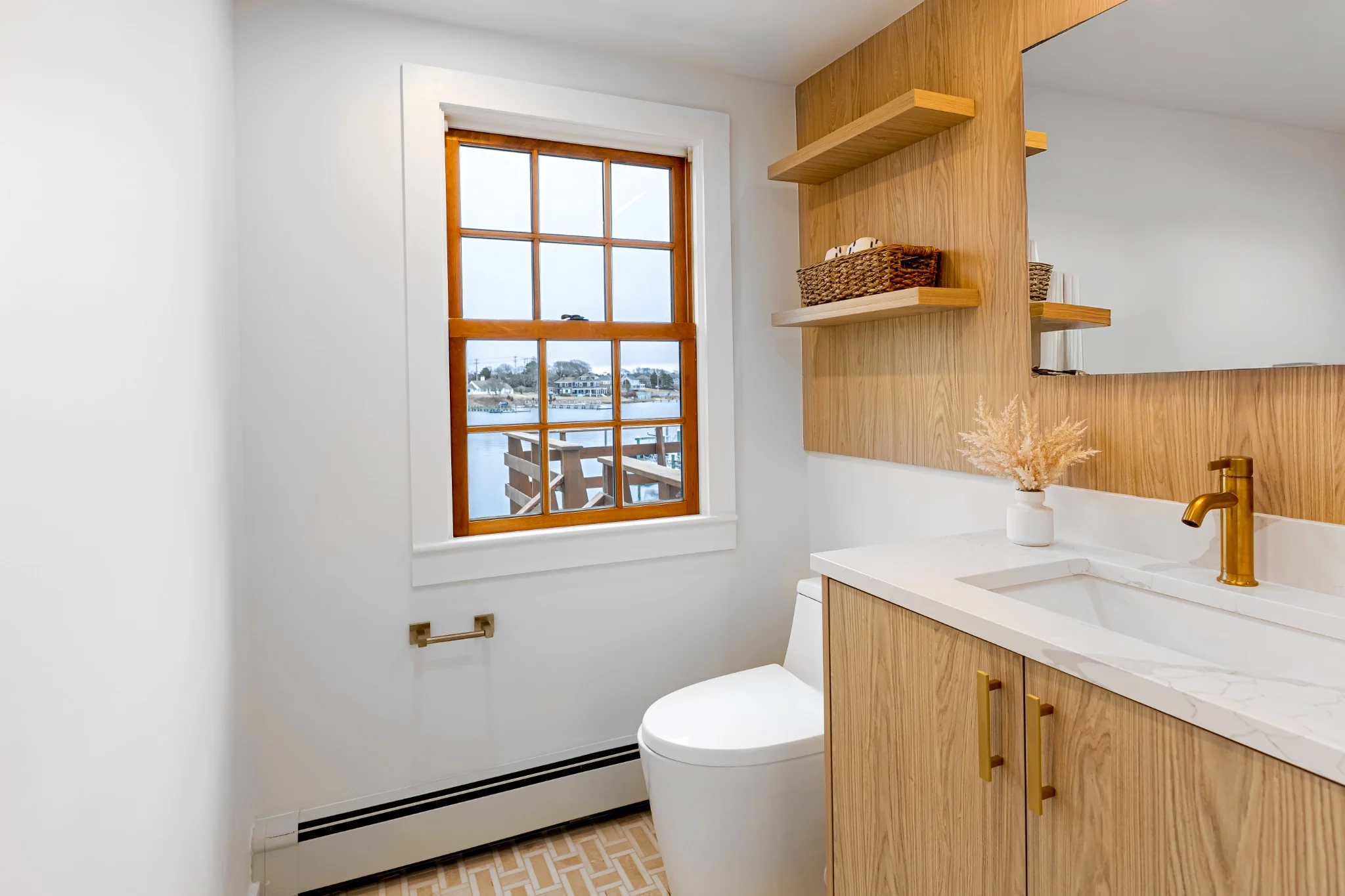 Bathroom vanity area with warm wood cabinetry, black fixtures, bright wall finish, and water view window.