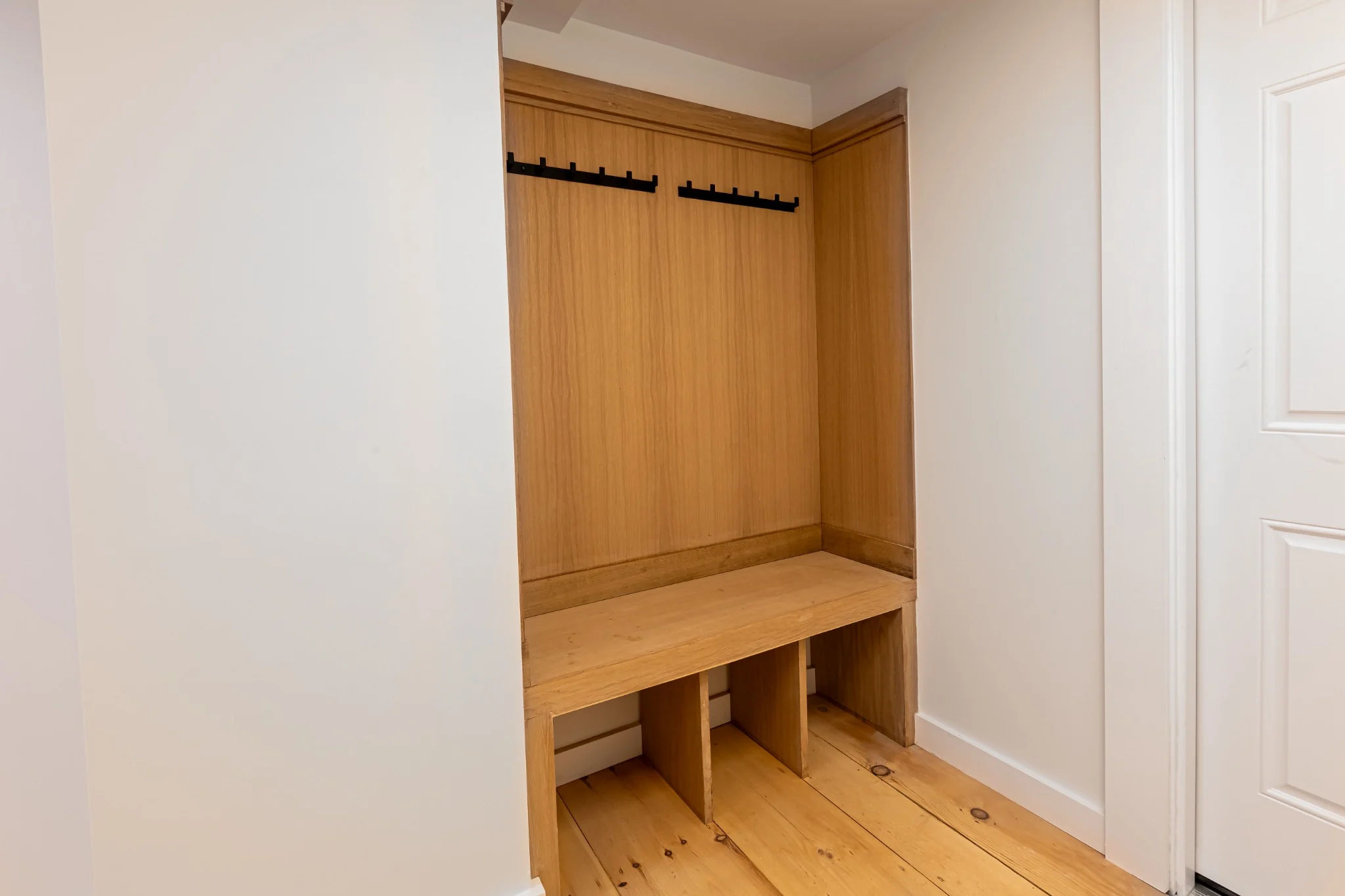 Custom mudroom bench with wood seat, coat hooks, storage cubbies, and clean built-in finish details.